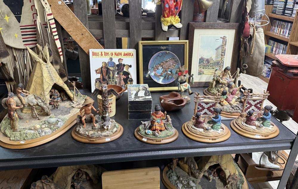 A table of collectible figurines and framed art in the antiques section