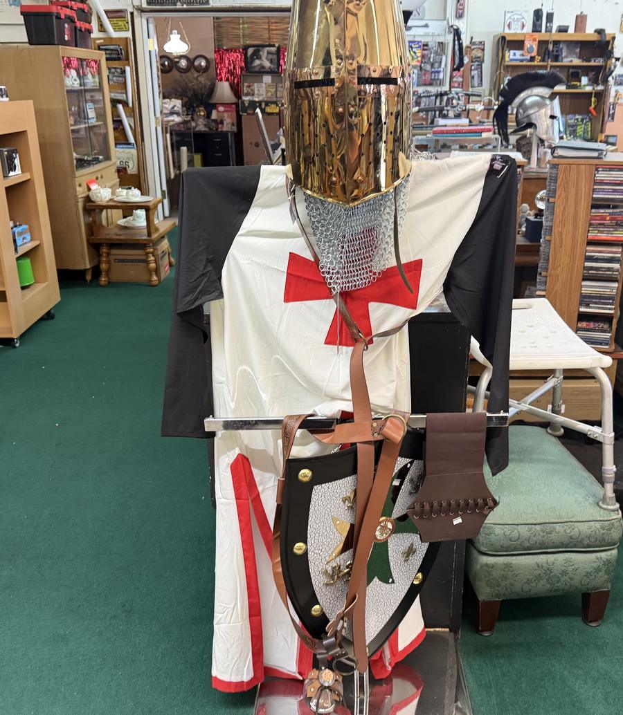 A full suit of knight armor with a shield standing in the middle of the store