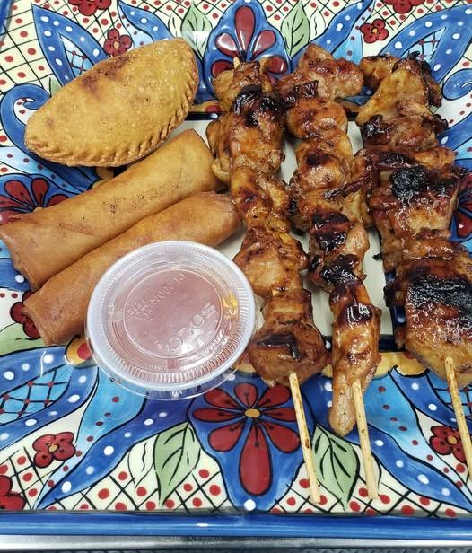 A hand painted platter of empanadas, crispy lumpia and grilled barbecue skewers with dipping sauce