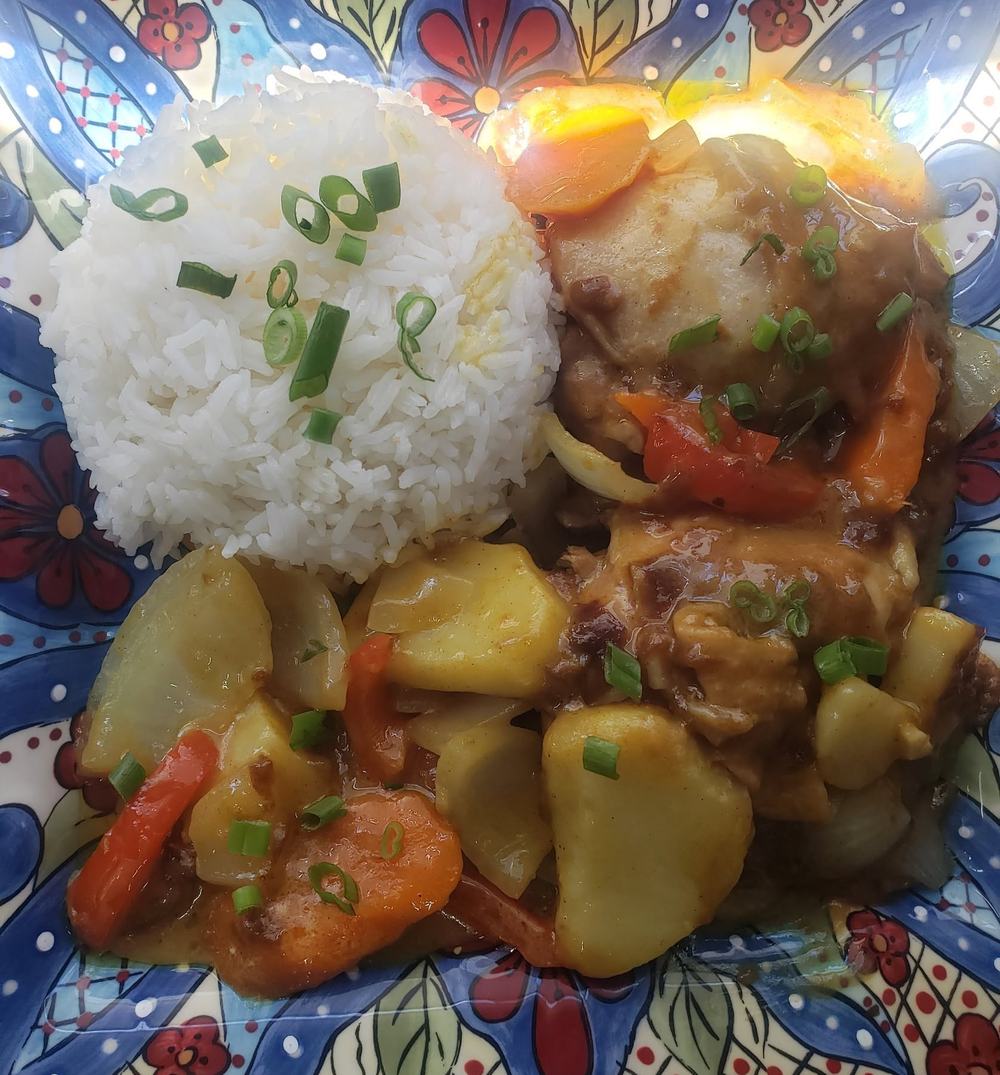 Chicken simmered with potatoes, carrots and peppers in a golden sauce, served with white rice