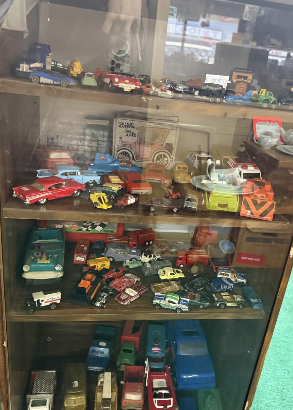 A glass cabinet full of vintage toy cars and trucks