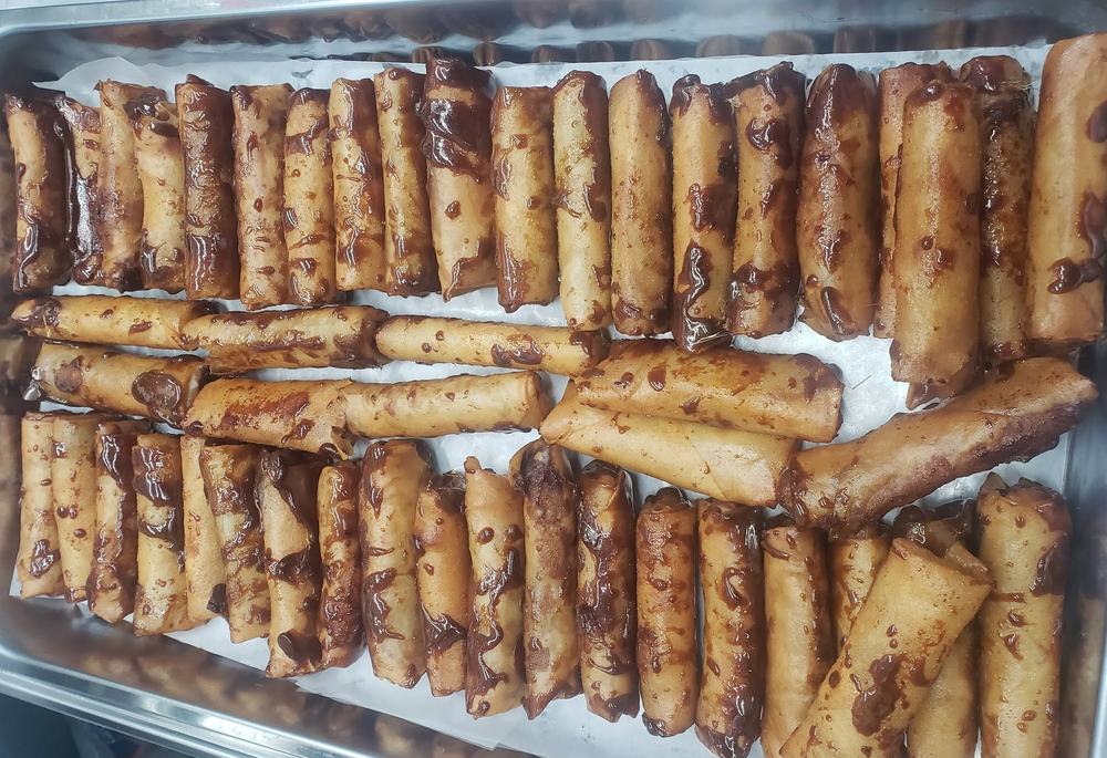 A tray packed with crispy turon banana rolls drizzled with caramel